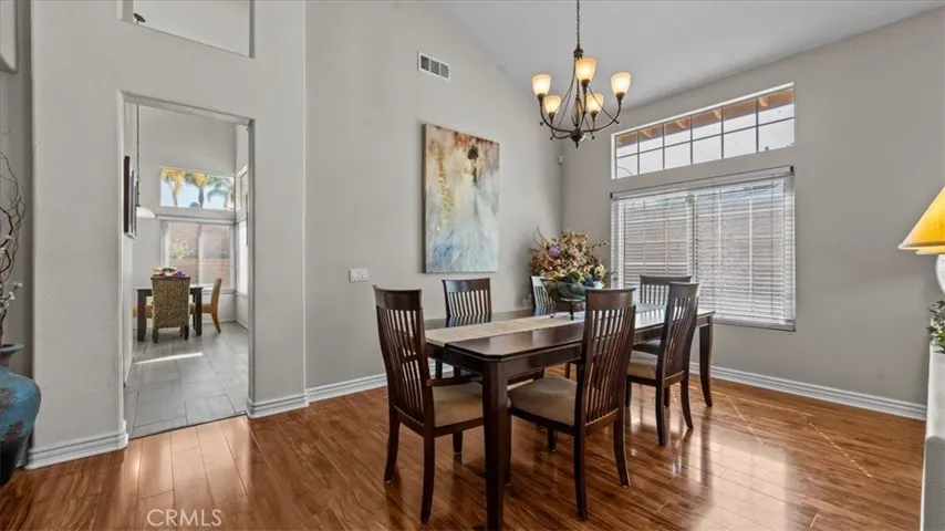 This formal dining space features vaulted ceilings, large windows, and warm wood flooring, creating an inviting setting for gatherings and everyday meals.