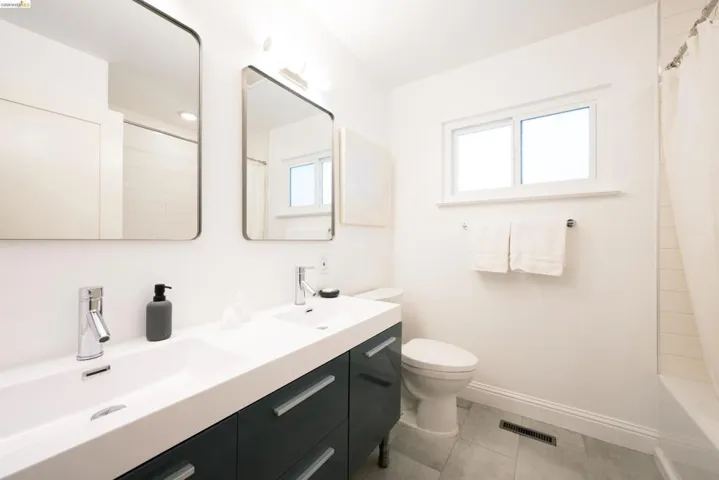 Bathroom featuring double vanity, shower / bath combo with shower curtain, and light tile patterned floors