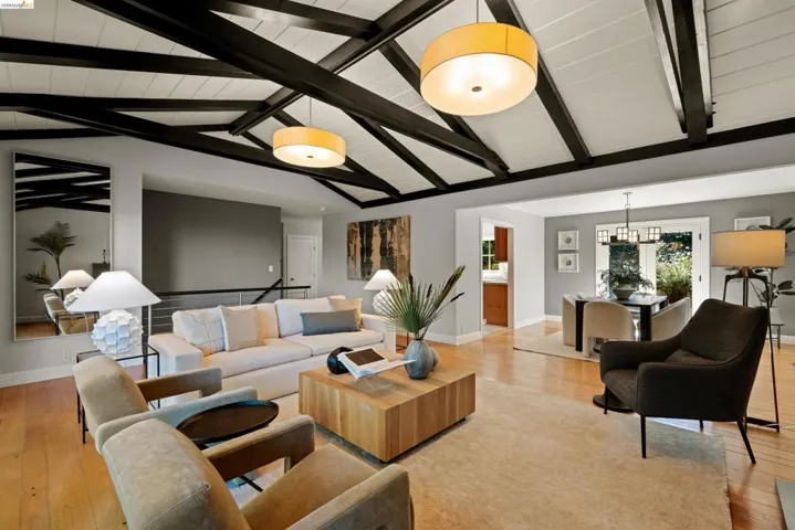 Living area with light wood-type flooring, suspended lighting, and beam ceiling