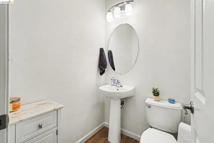 Bathroom featuring dark wood-style floors and a textured wall