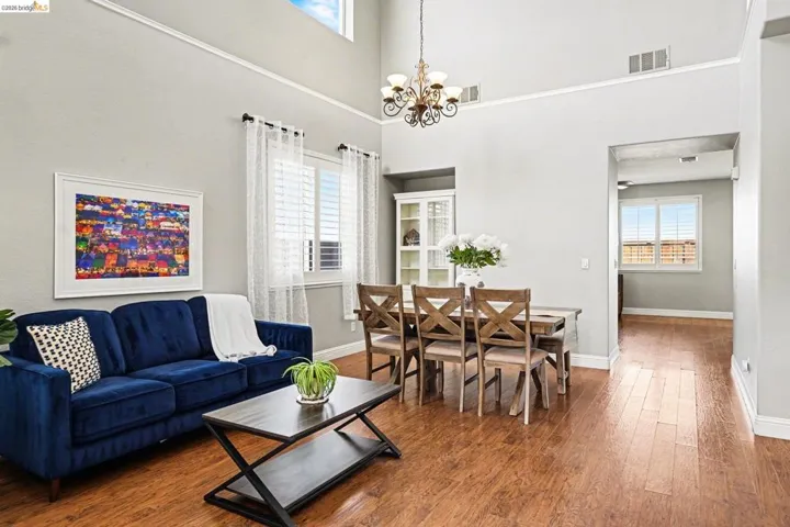 Living area with wood-type flooring, hanging lights, and a high ceiling