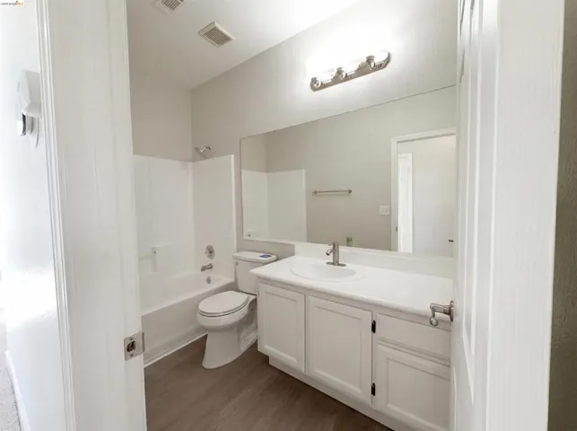 Full bath with vanity, shower / washtub combination, and dark wood-style flooring