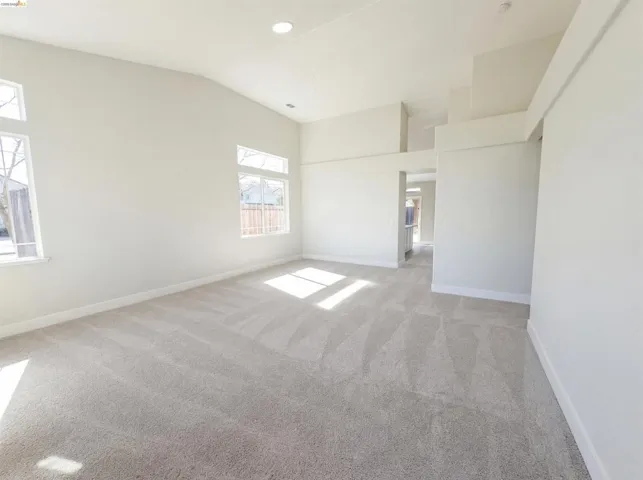 Spare room with light carpet and vaulted ceiling