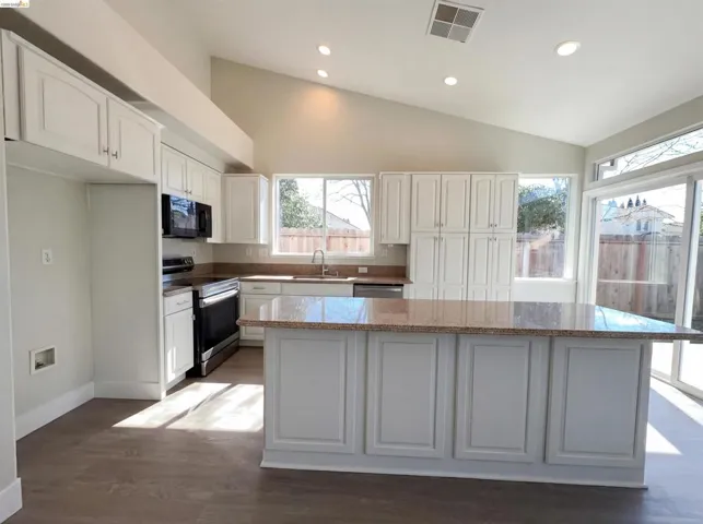 Kitchen featuring stainless steel appliances, white cabinetry, recessed lighting, a kitchen island, and lofted ceiling