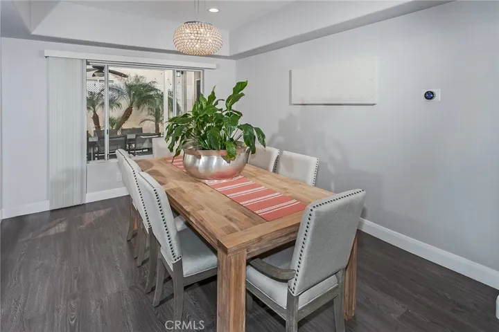 The dining room is filled with natural sunlight from a large window overlooking the outdoor seating area, creating a bright and inviting setting for everyday meals, celebrations, and entertaining.