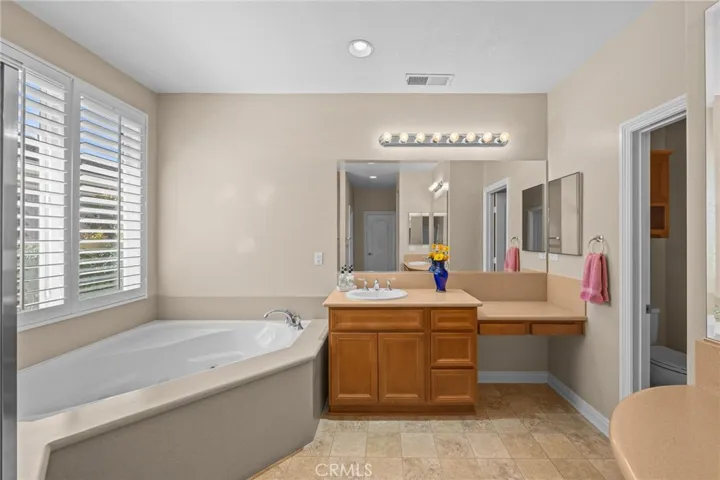 2nd sink along with the jetted tub in the primary suite.   Notice the wood plantation shutters also