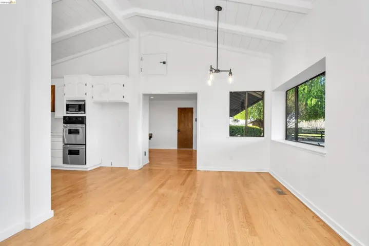 Unfurnished living room featuring light wood-style floors and lofted ceiling