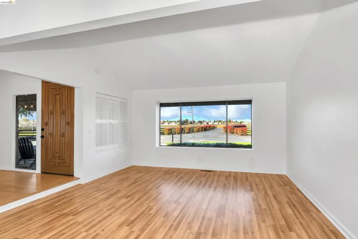 Empty room featuring light wood-type flooring and vaulted ceiling