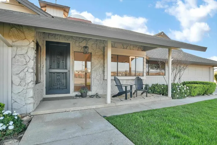 View of exterior entry with covered porch, an attached garage, and a yard