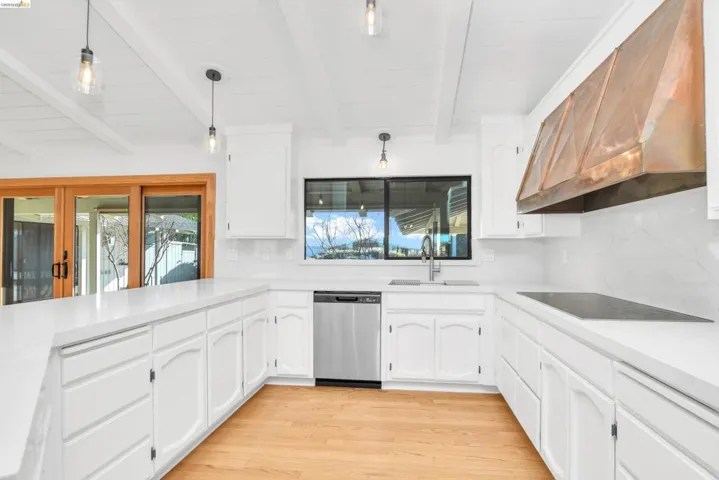Kitchen featuring pendant lighting, range hood, white cabinetry, dishwasher, and light wood-type flooring