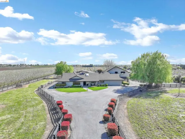 View of front facade featuring a fenced front yard, a view of countryside, agricultural plots, and a garage