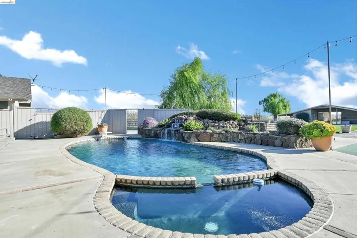 Combined pool / hot tub with a fenced backyard and a patio