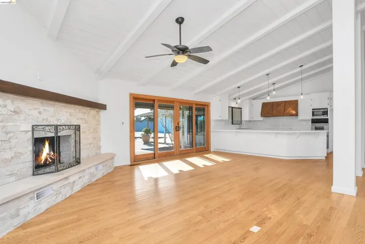 Unfurnished living room featuring lofted ceiling, a ceiling fan, light wood finished floors, and a fireplace
