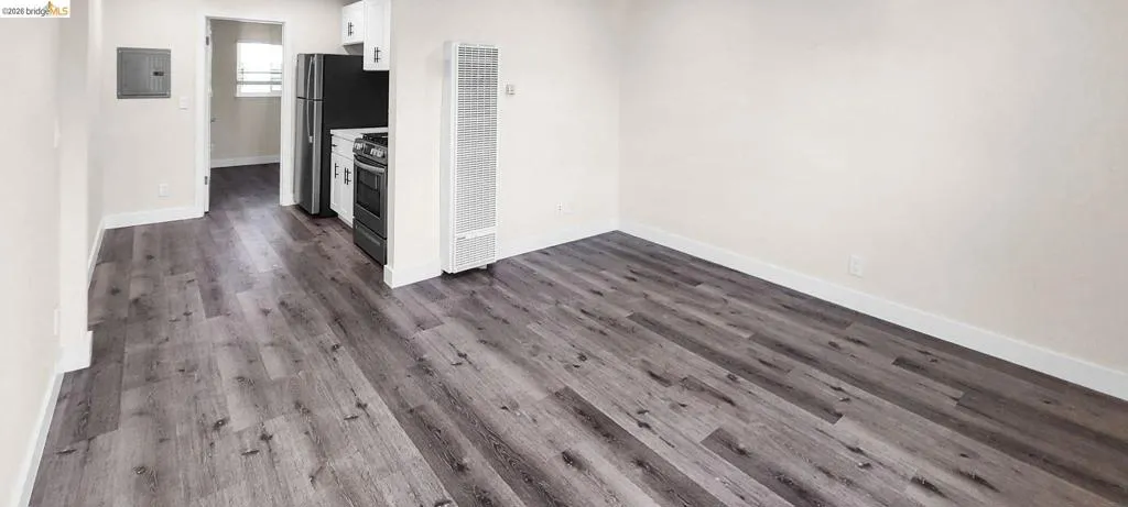 Kitchen with a heating unit, stainless steel appliances, dark wood finished floors, electric panel, and light countertops
