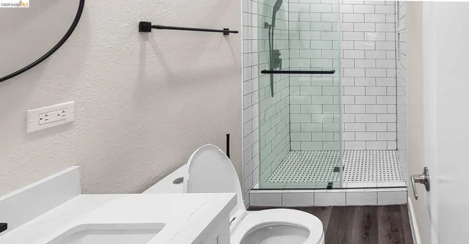 Bathroom featuring a textured wall, a shower stall, vanity, and dark wood finished floors