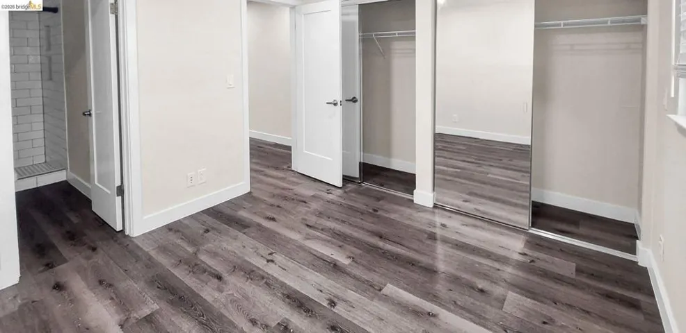 Unfurnished bedroom with two closets and dark wood-style flooring