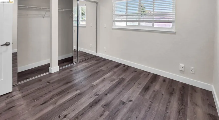 Unfurnished bedroom with dark wood-style floors and multiple closets