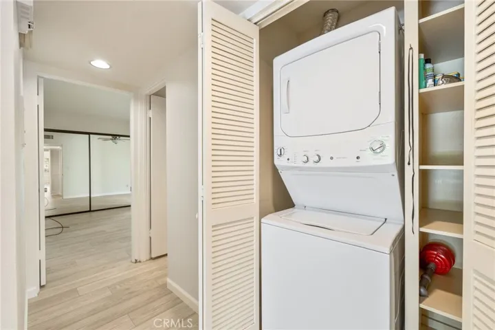 Washer and dryer in hall closet with extra shelving.