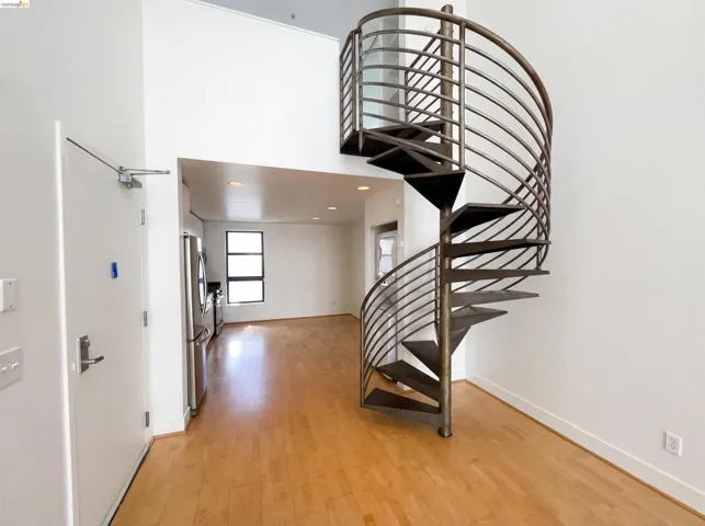 Staircase featuring wood finished floors, a high ceiling, and recessed lighting