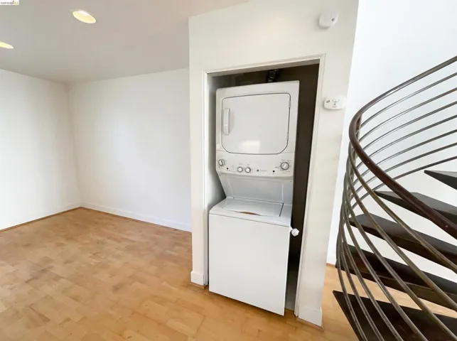 Laundry area featuring light wood-type flooring, stacked washer / drying machine, and recessed lighting