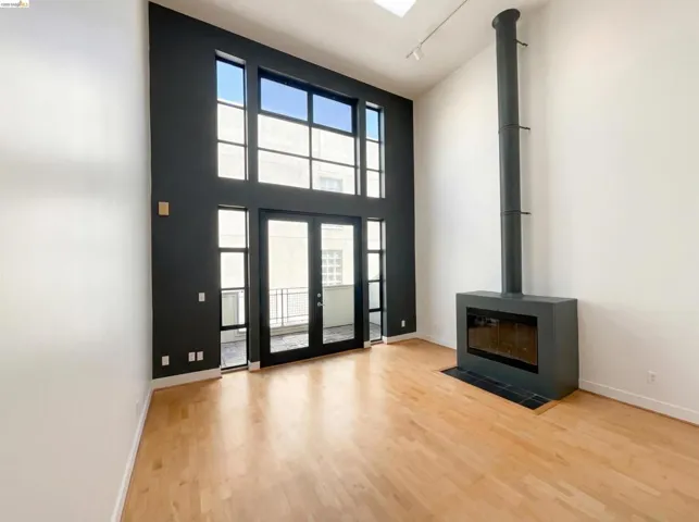 Entryway featuring a high ceiling, a wood stove, light wood finished floors, and french doors