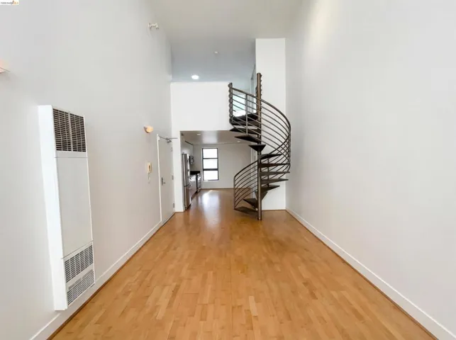 Hallway with a high ceiling, a heating unit, and light wood finished floors