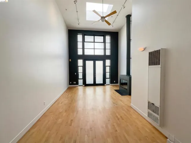 Entryway with a skylight, light wood finished floors, a heating unit, a high ceiling, and a wood stove