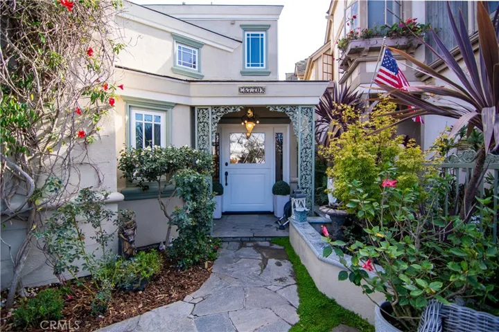 Elegant patio surrounded by lush, meticulously landscaped gardens leading to a charming Dutch-style front entry.