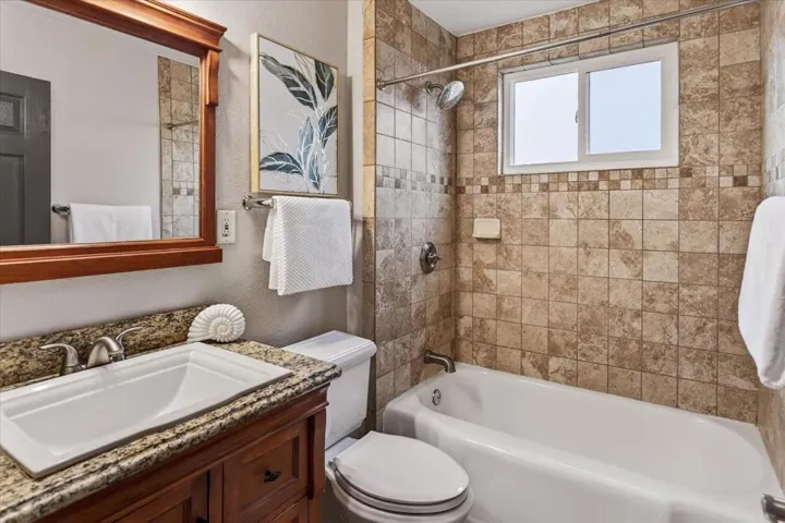 Bathroom with granite counter vanity and shower over tub.