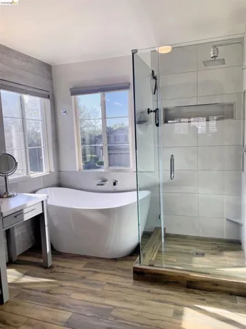 Full bathroom with a freestanding bath, a stall shower, and wood finished floors