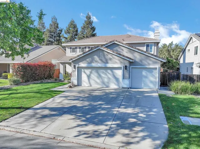 Traditional-style home with an attached garage, a tile roof, stucco siding, and concrete driveway