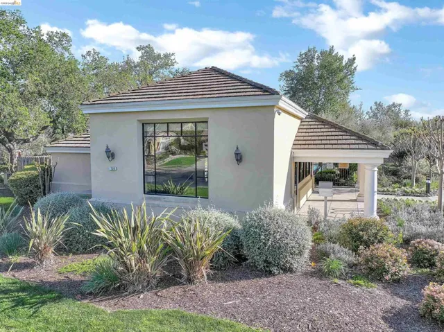 View of side of property with a tile roof, stucco siding, and a patio area