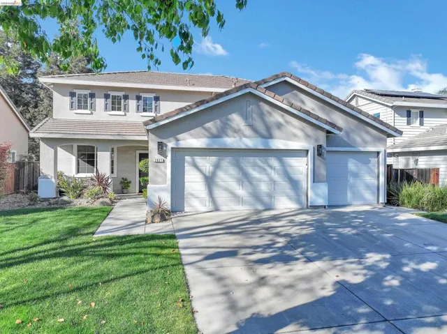 Traditional home featuring a garage, stucco siding, a tiled roof, driveway, and covered porch