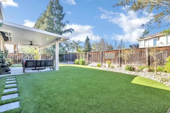 Fenced backyard with ceiling fan and a patio