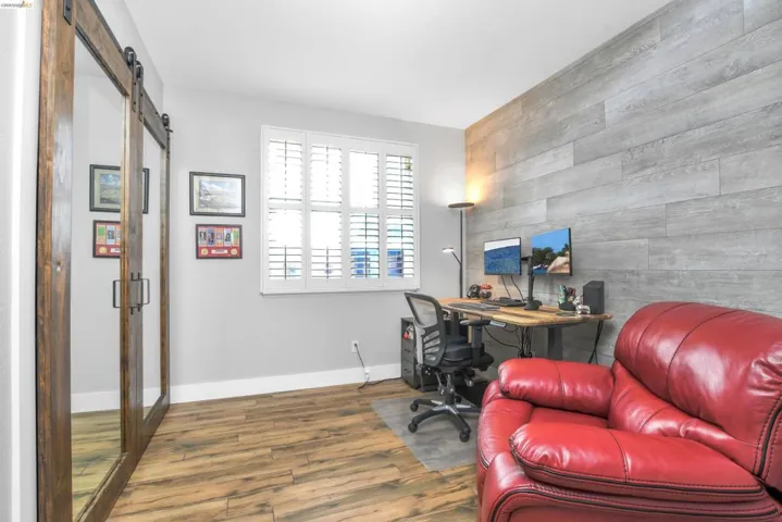 Office space with an accent wall, a barn door, wooden walls, and wood finished floors