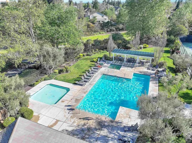 Community pool with a patio, a pergola, and view of wooded area