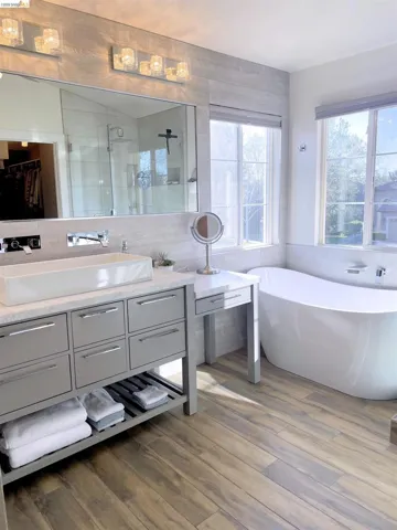 Full bath with vanity, a shower stall, a freestanding tub, dark wood-style flooring, and tile walls