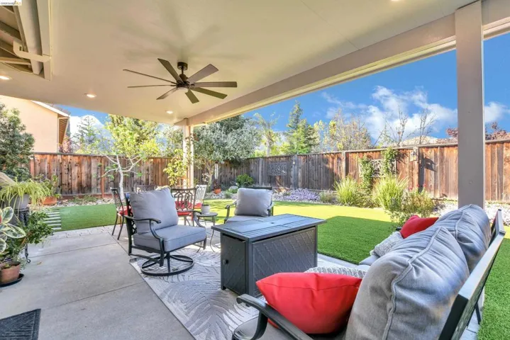 Fenced backyard with a patio, ceiling fan, and outdoor furniture