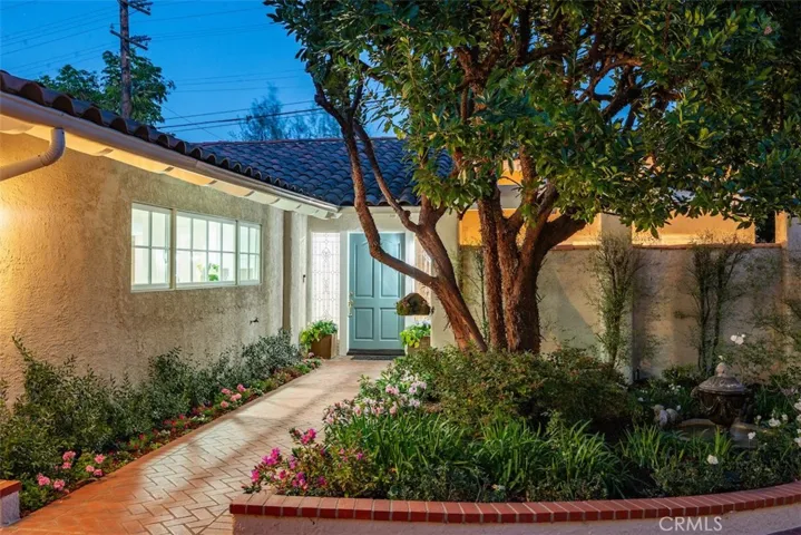 Lushly landscaped entry with fountain and beautiful strawberry tree