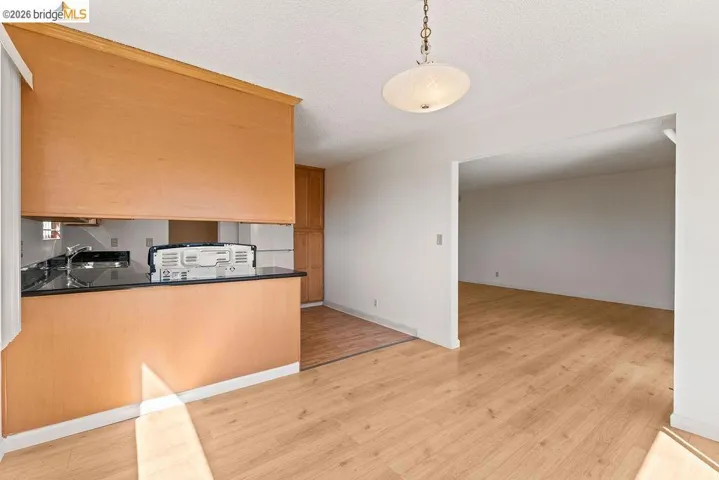 Kitchen with light wood finished floors, freestanding refrigerator, a textured ceiling, and pendant lighting