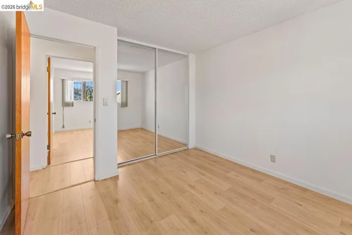 Unfurnished bedroom featuring light wood-type flooring, a textured ceiling, and a closet