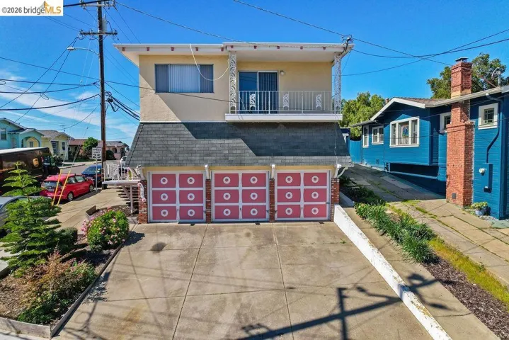 View of front of property featuring a balcony, roof with shingles, concrete driveway, stucco siding, and brick siding
