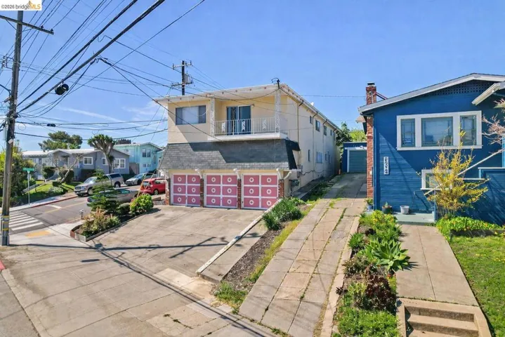 View of front of property featuring driveway, a chimney, a balcony, and an attached garage