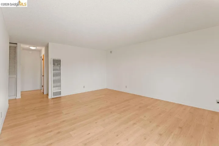 Unfurnished room with a heating unit, light wood-style floors, and a textured ceiling