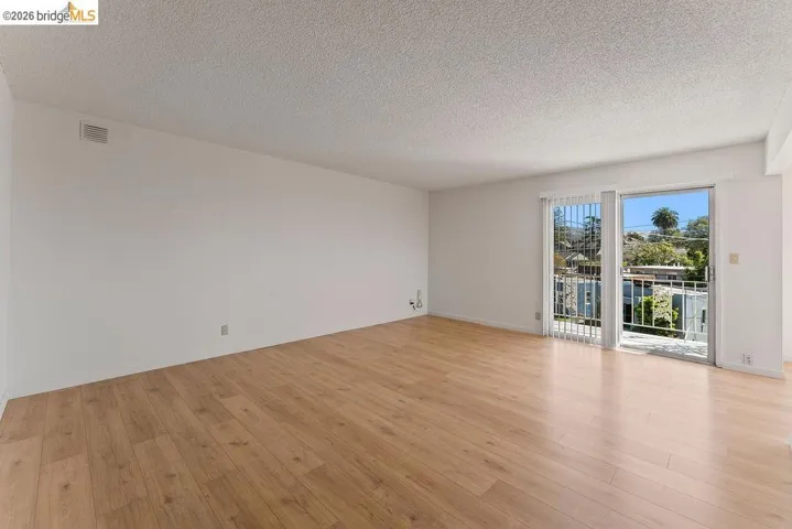 Spare room with a textured ceiling and light wood finished floors