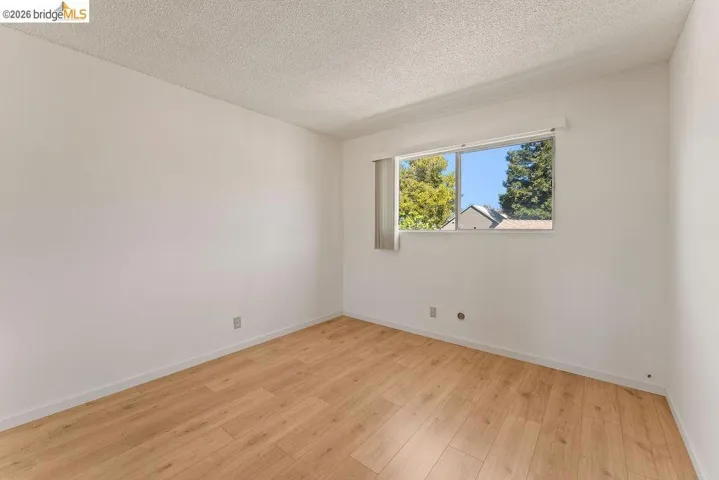 Empty room featuring light wood-type flooring and a textured ceiling