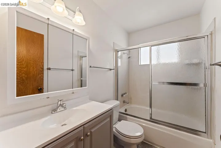 Bathroom featuring vanity and bath / shower combo with glass door