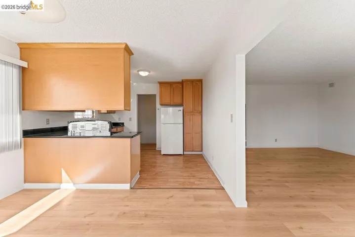 Kitchen featuring light wood-type flooring, freestanding refrigerator, a textured ceiling, and open floor plan