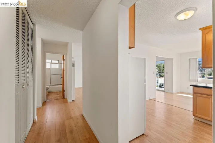 Corridor with light wood finished floors and a textured ceiling