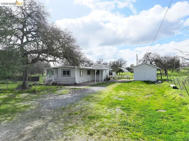 Back of house with a patio, driveway, and an outbuilding